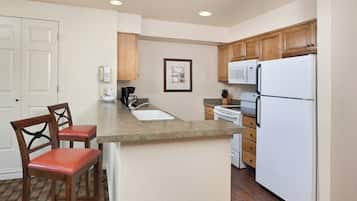 A kitchen with a central island, wooden cabinets, a white refrigerator, and a coffee maker.