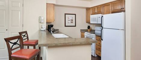 A kitchen with a central island, wooden cabinets, a white refrigerator, and a coffee maker.