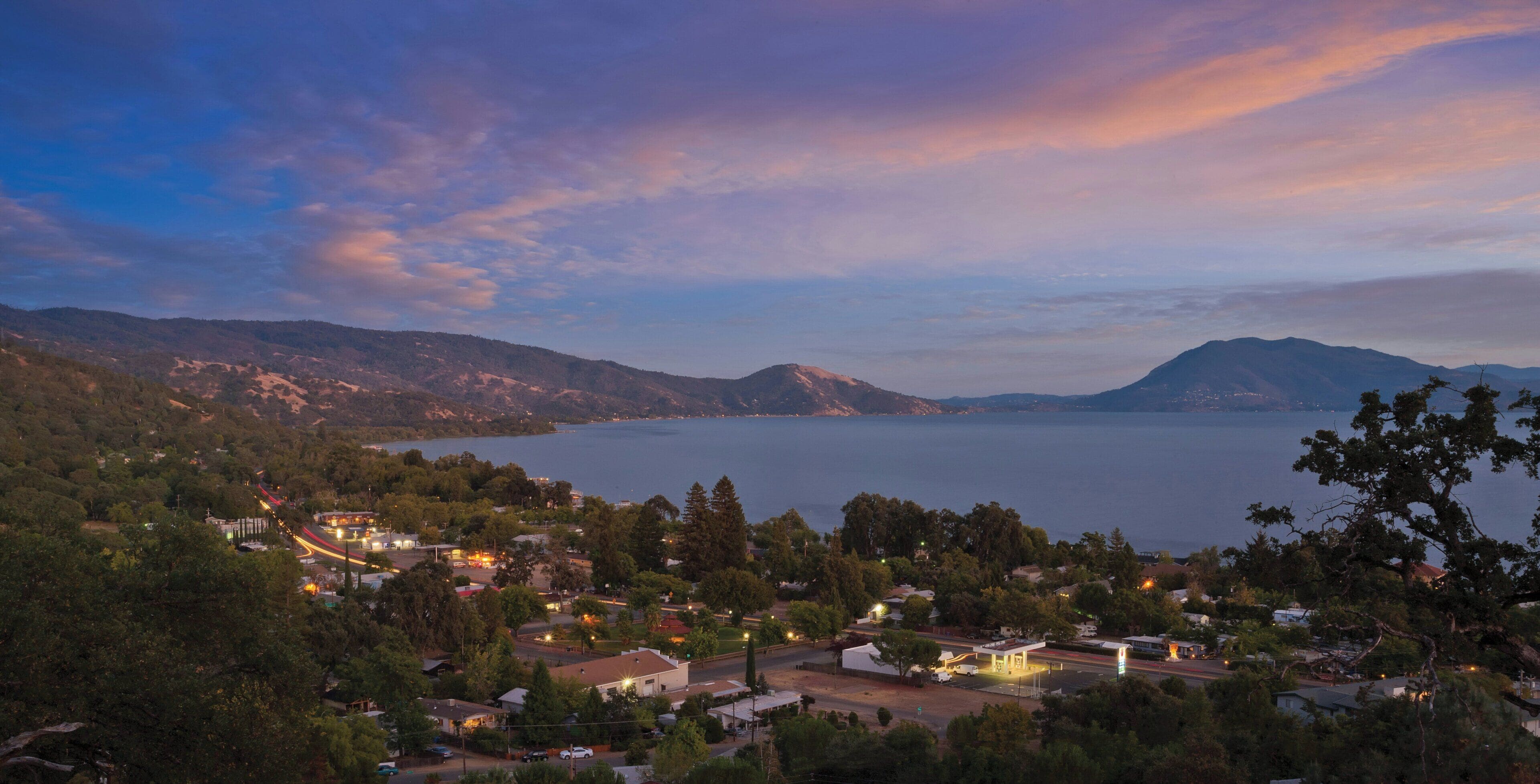 Un pueblo costero con vista al mar y montañas al fondo.