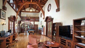 A spacious room with wooden beams, a pool table, comfortable seating, a television, and a bookshelf. - WorldMark Clear Lake (Nice)