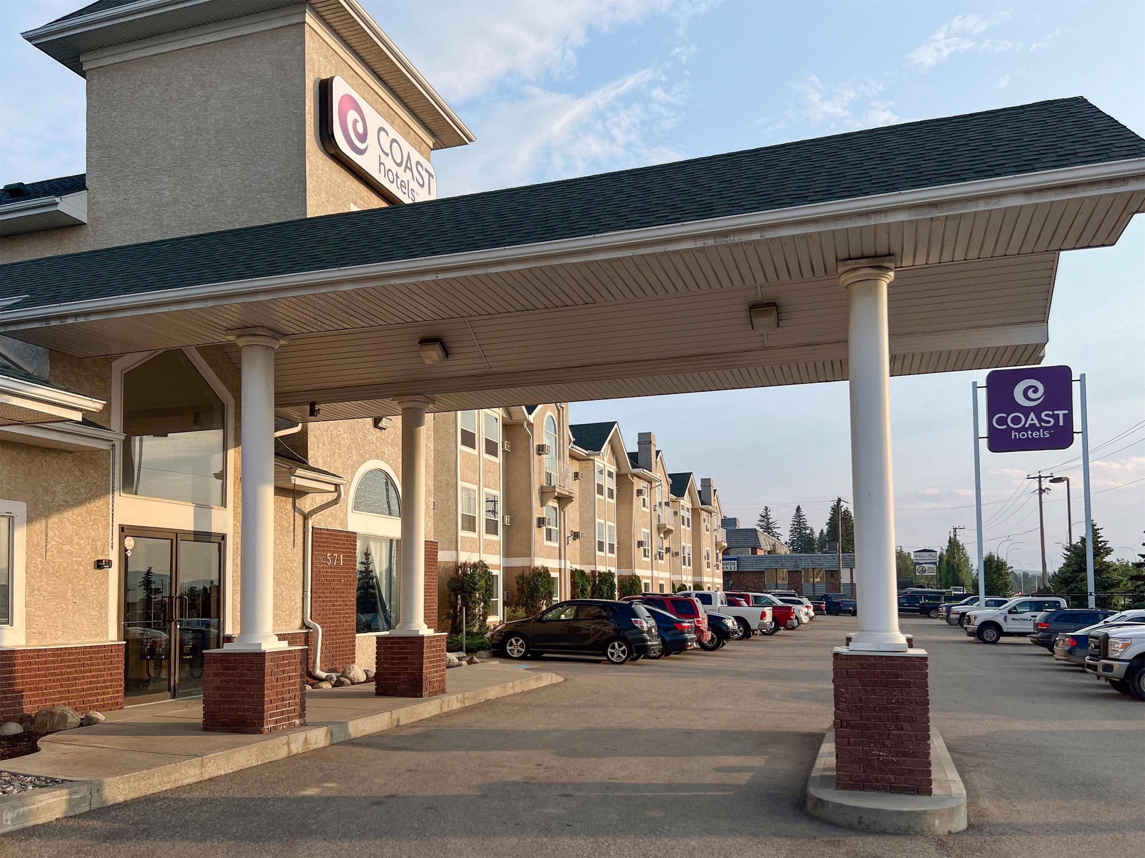 A hotel with a covered parking area, multiple floors, and a prominent sign.