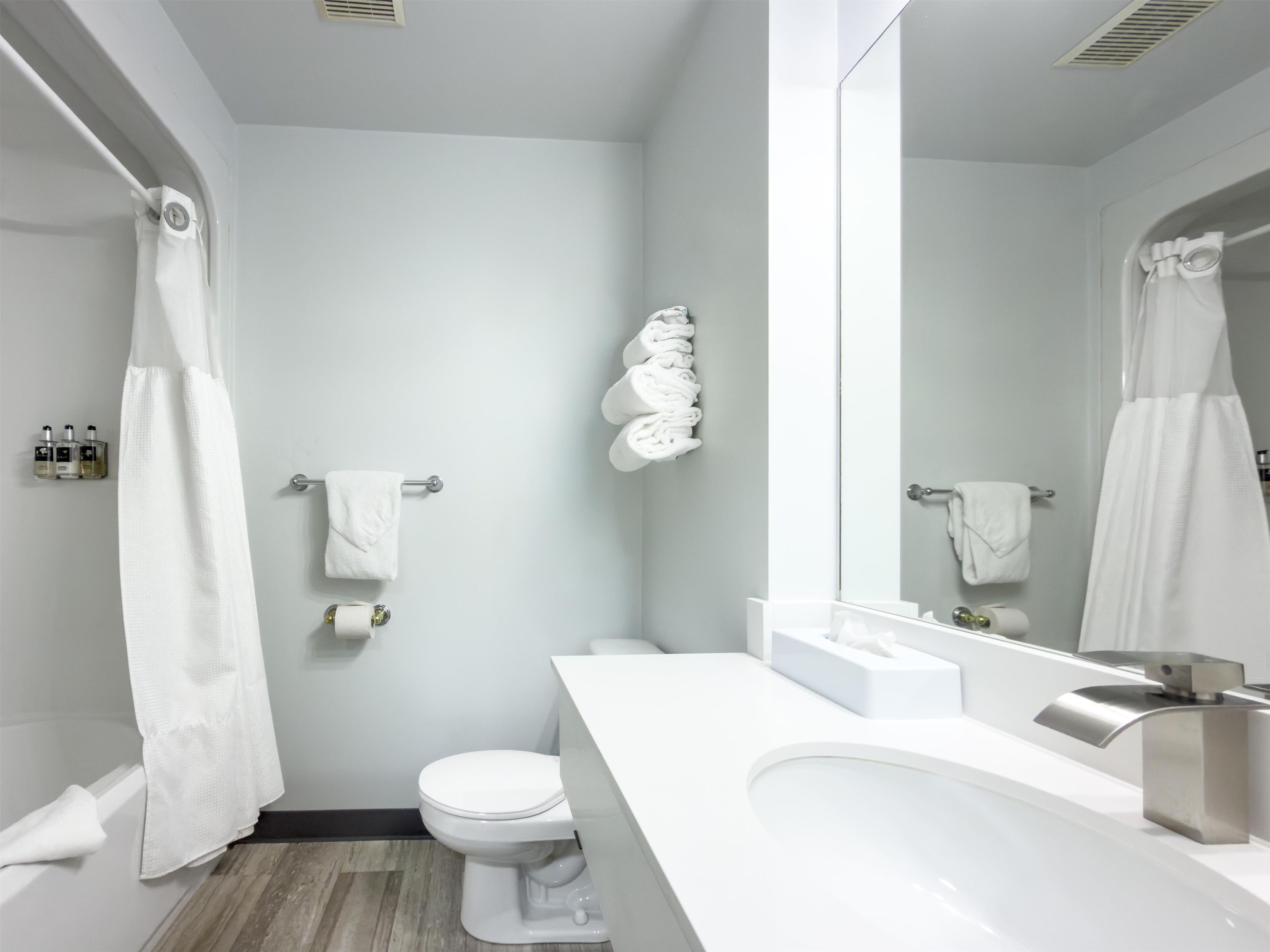 Un baño moderno con inodoro blanco, lavamanos y zona de ducha.