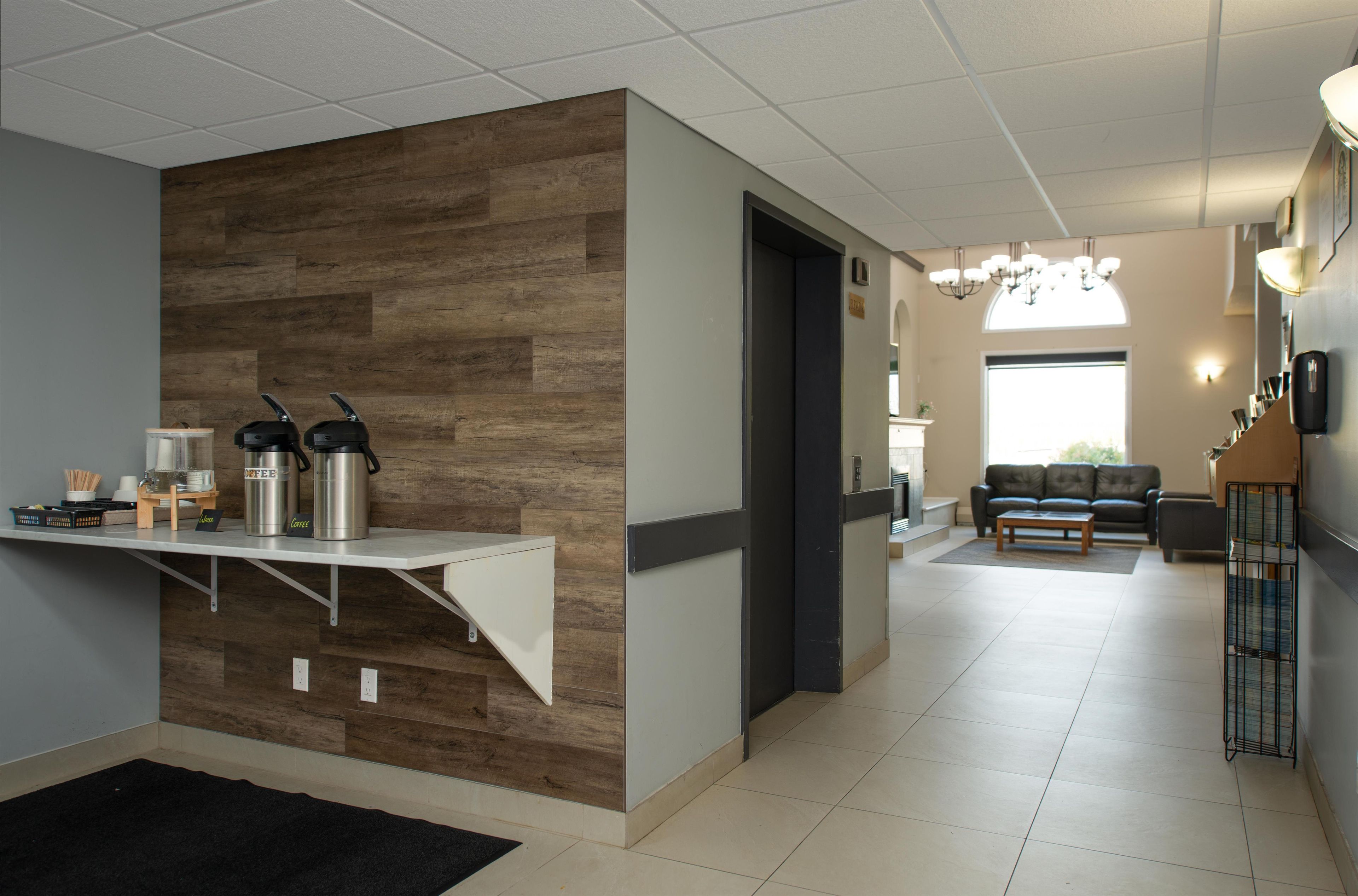 Un moderno vestíbulo de hotel con una pared de acento de madera, una recepción, una zona de estar con sofá y un rincón de café.