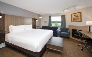 Quarto de hotel com uma cama grande, uma escrivaninha com cadeira, um sofá e uma lareira.
