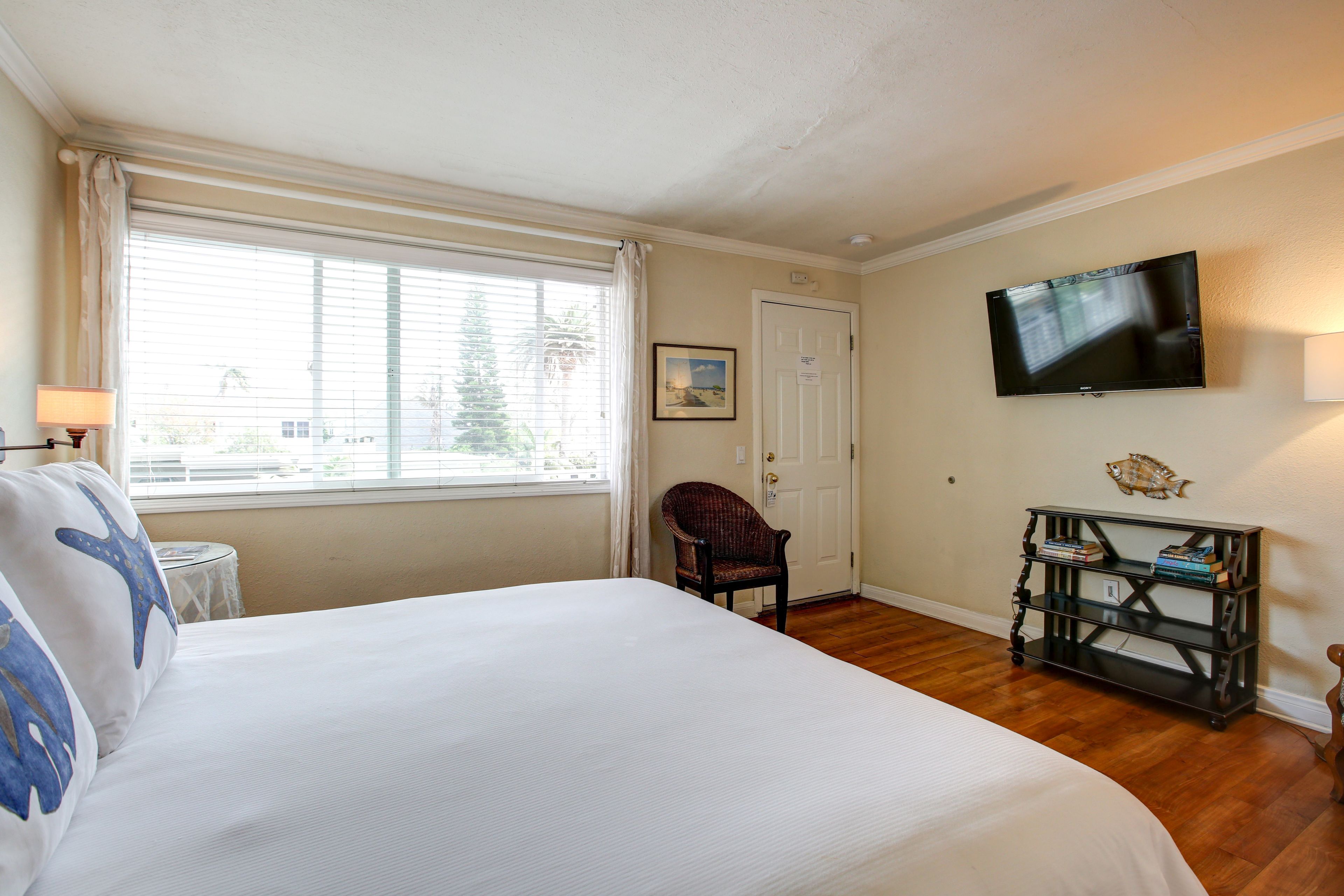 Un dormitorio con una cama grande, una silla, un televisor y una mesita.