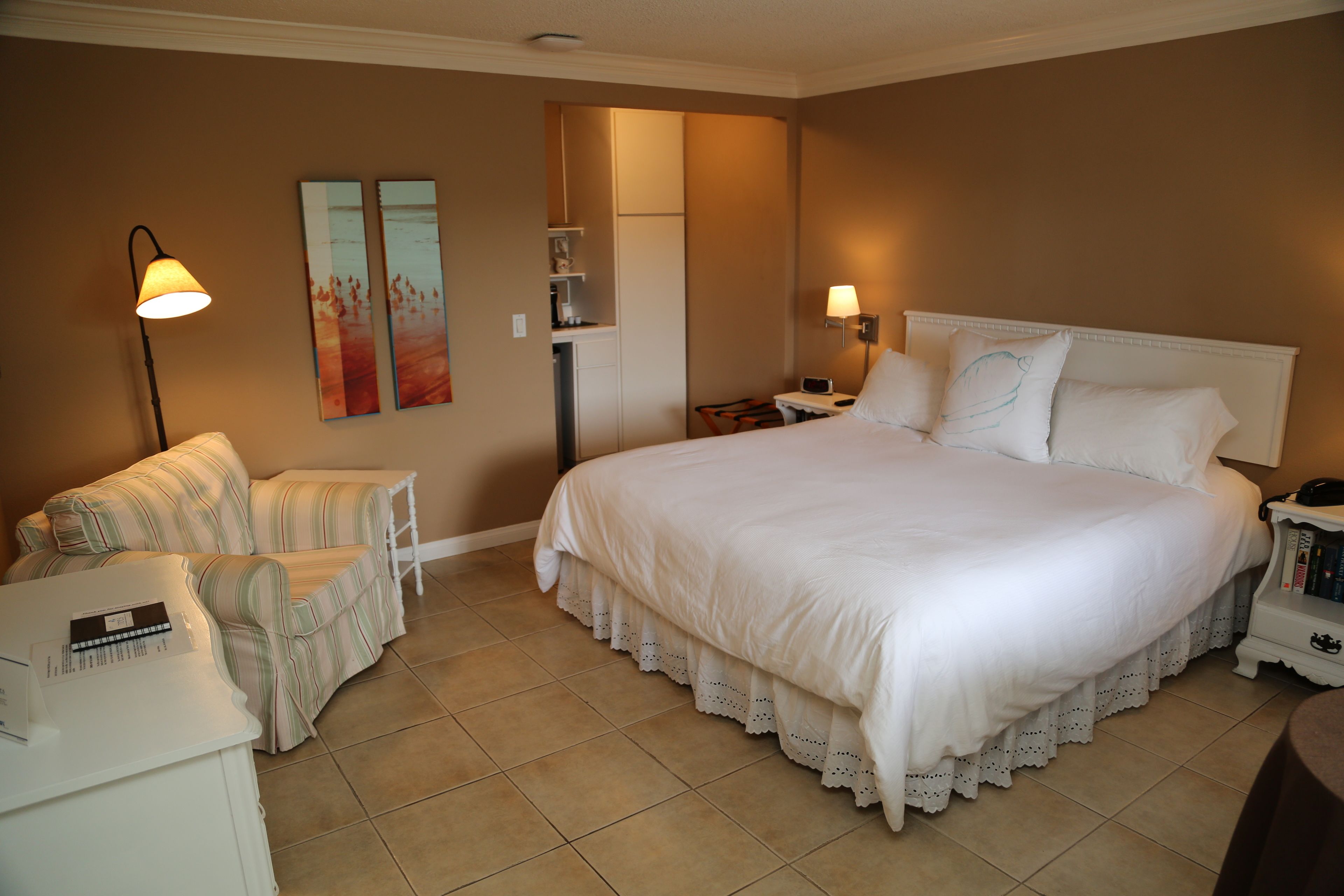 Quarto de hotel com uma cama grande, um sofá, uma escrivaninha e uma mesa de cabeceira.