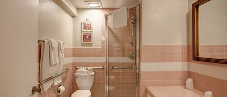 A bathroom with a toilet, a shower with a glass door, a sink, and a mirror.