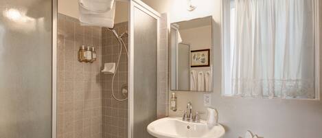 A bathroom with a shower, sink, and toilet.