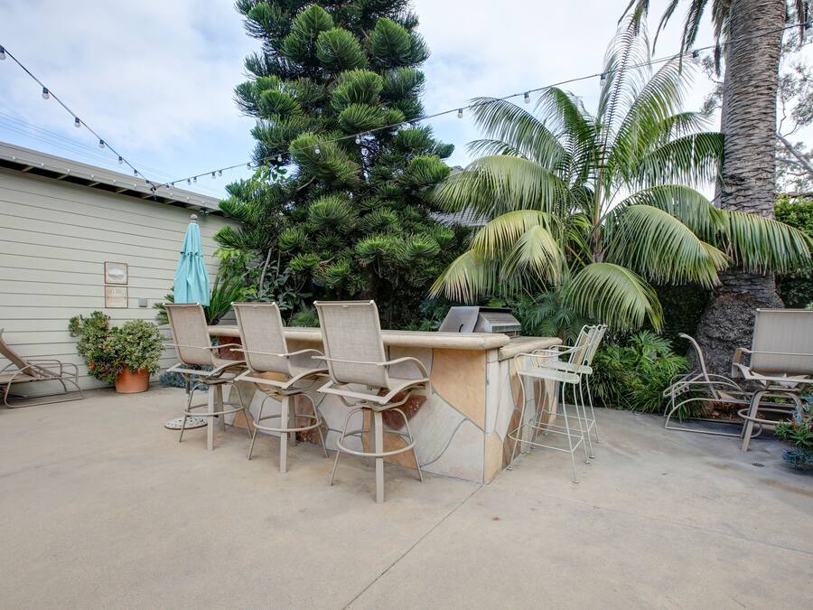 An outdoor patio with a bar area, chairs, and potted plants.