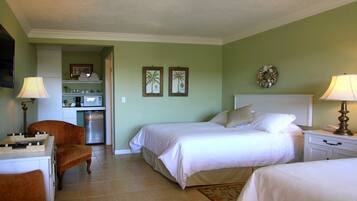 A hotel room with a bed, a chair, a desk, a microwave, and a refrigerator.