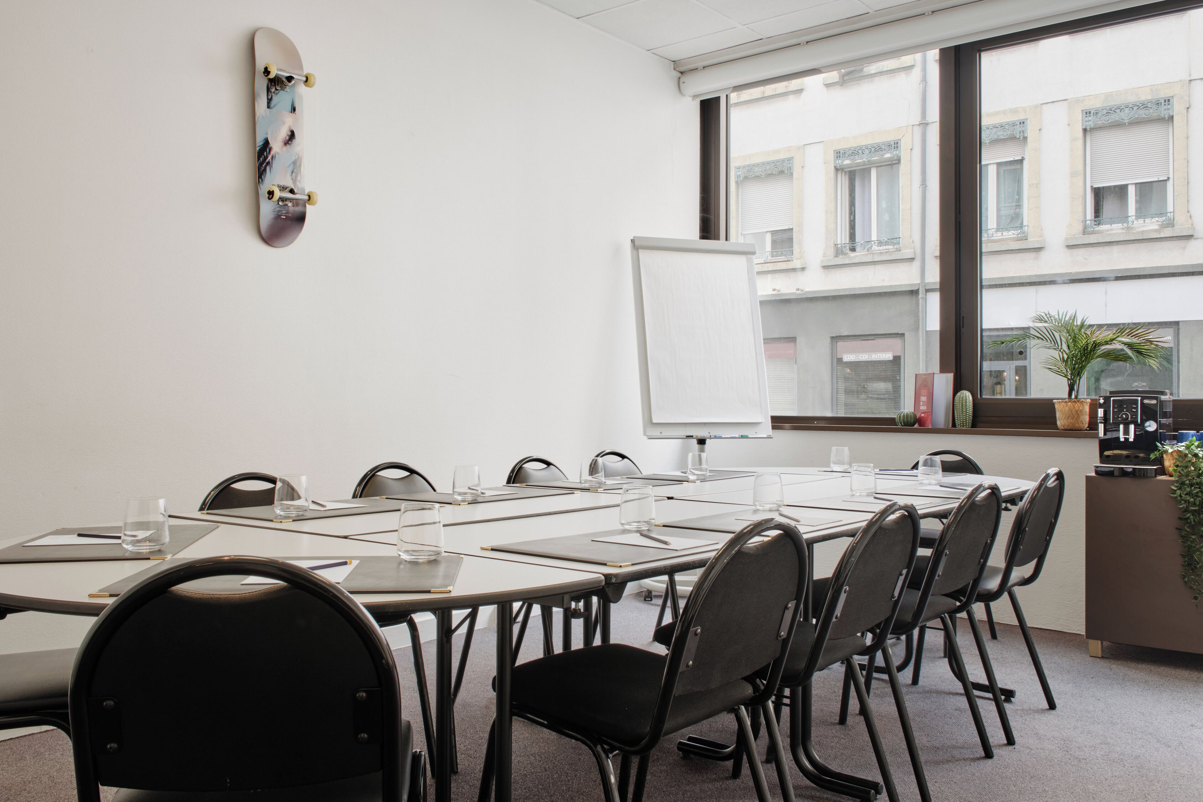 Una sala de conferencias con una pizarra, un monopatín en la pared y vistas de edificios a la ventana.