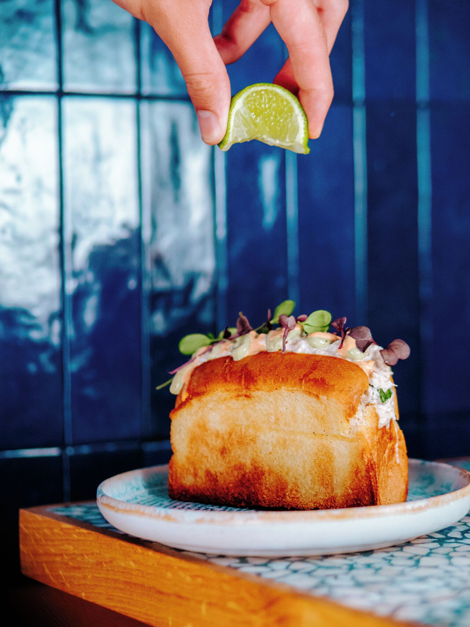 A sandwich on a plate with a lime wedge on top.