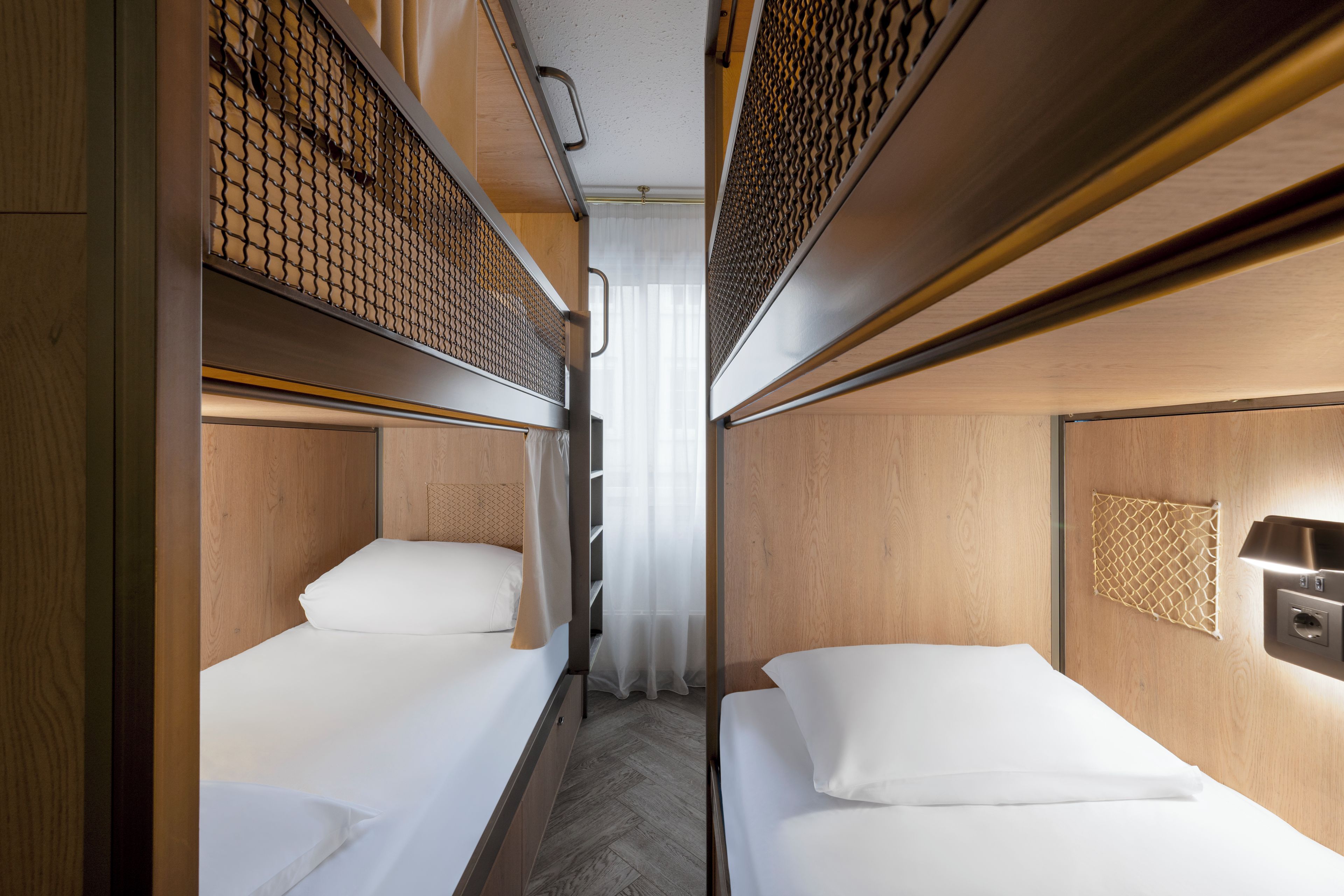 A narrow train compartment with two single beds, wooden paneling, and a small overhead shelf.