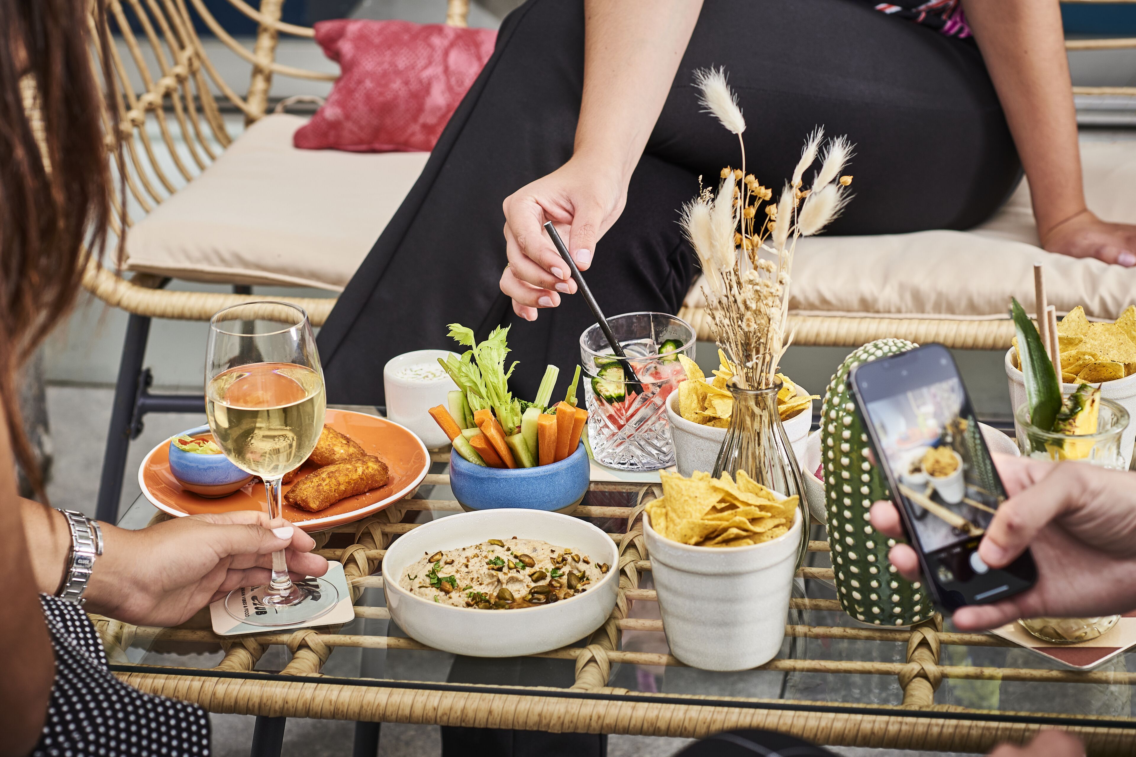 Une table à manger avec différents plats, un verre de vin et un téléphone intelligent.