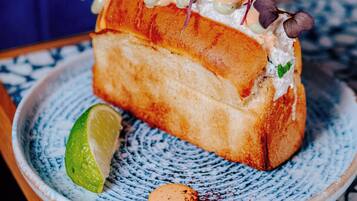 A sandwich on a ceramic plate with a lime wedge and a small red pepper.