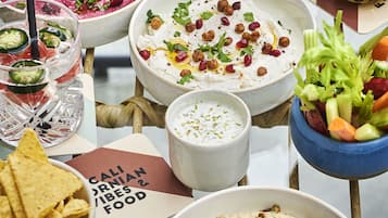 Une table avec divers aliments, notamment des sauces et des amuse-gueules, et un verre contenant une boisson claire.