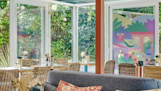 Amplia habitación con un ventanal grande, un sofá con cojines estampados y una mesa con adornos.