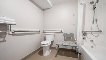 A bathroom with a toilet, grab bars, a shower with a handheld showerhead, and a bathtub.
