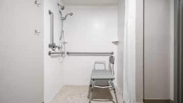 A shower area with a grab bar, a showerhead, and a shower seat.