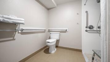A bathroom with a toilet, grab bars, a shower area, and a towel rack.