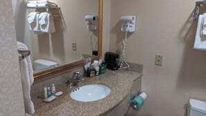 A bathroom with a sink, mirror, towel rack, hair dryer, and toilet.