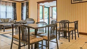 A dining area with a table and chairs, a sofa, and a view through a door.