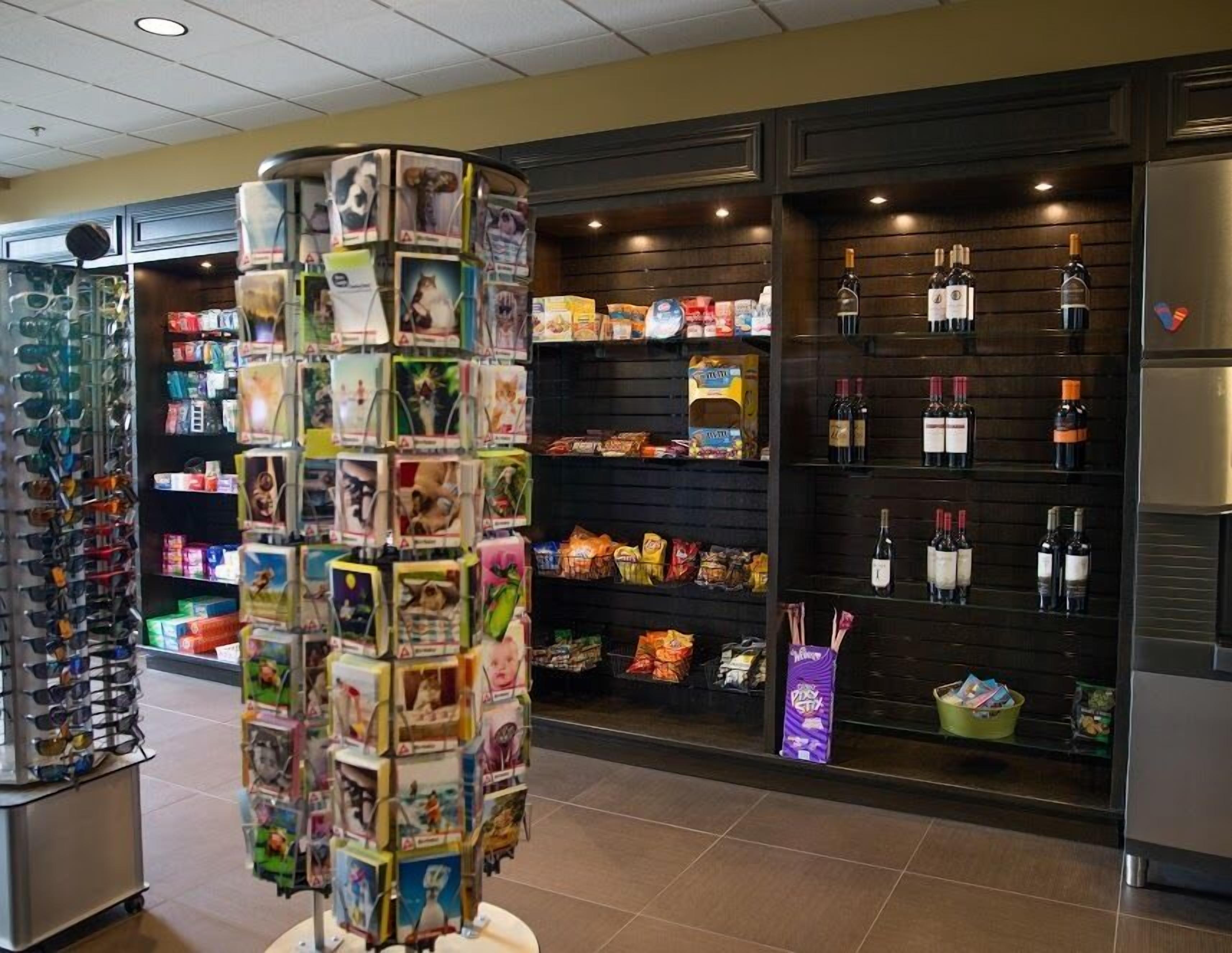 A retail area with shelves stocked with snacks, beverages, and a display of sunglasses.