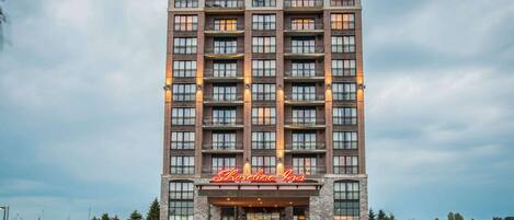 A multi-story hotel with a prominent entrance and a neon sign.