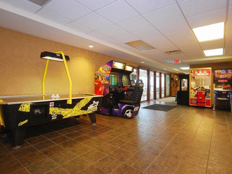 A hallway with a pool table, arcade games, and a vending machine.
