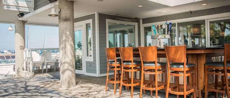 An outdoor seating area with a bar, wooden chairs, and a sign for 'The Lake House'.