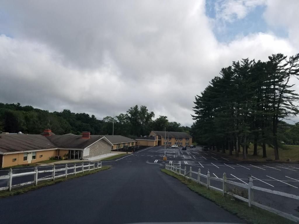A parking lot with a building on the left and trees on the right.