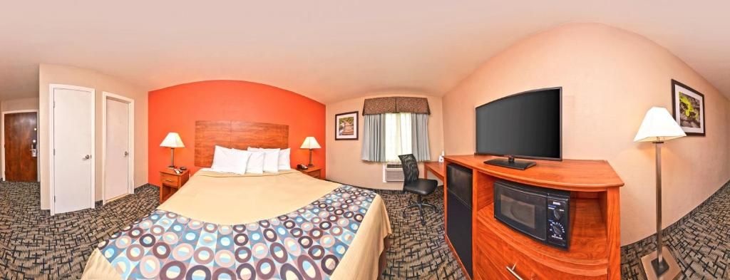 Een hotelkamer met een bed, televisie, bureau en een magnetron.