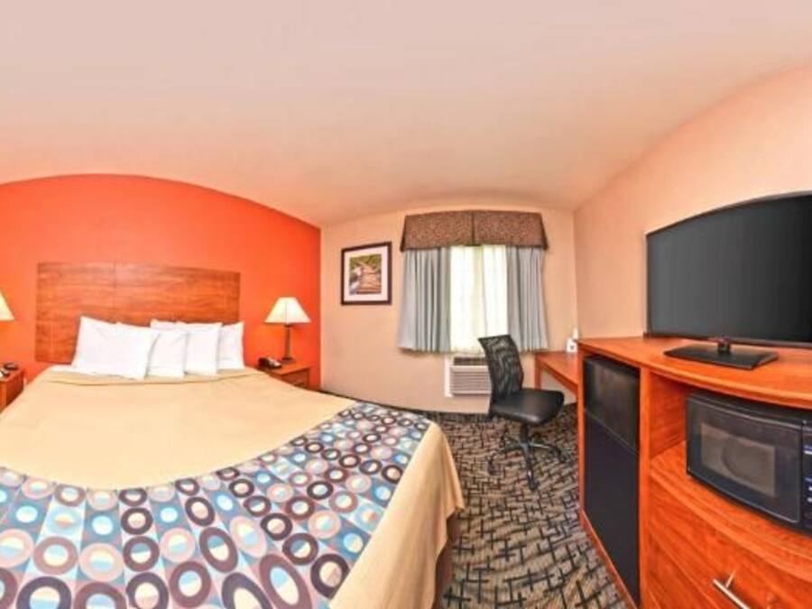 Een hotelkamer met een bed, televisie, bureau en een magnetron.