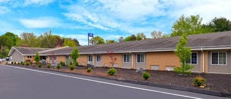 A row of motel buildings with a paved driveway and landscaped areas.