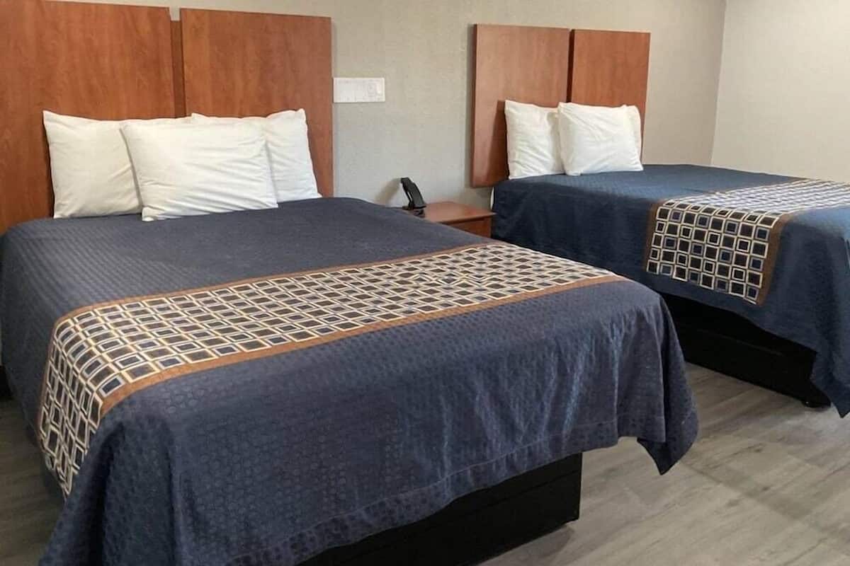 Two twin beds with matching headboards and footboards, a bedside table with a phone, and a patterned bedspread.