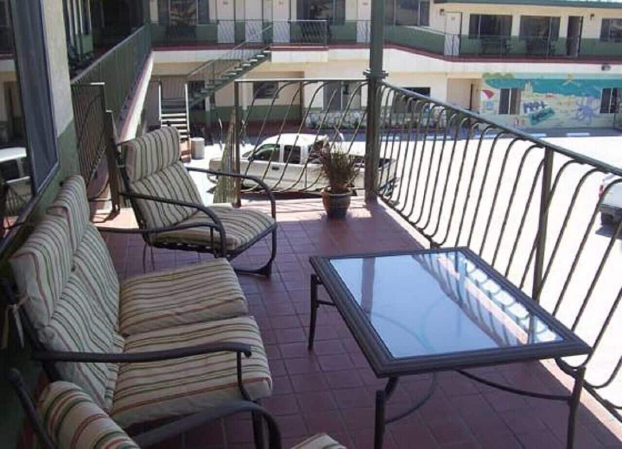 A balcony with striped sofas, a glass table, and a potted plant.