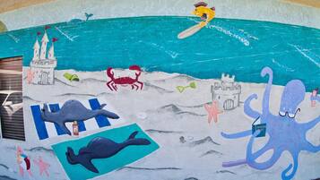 A mural with a castle, a whale, a crab, and an octopus on a beach scene.
