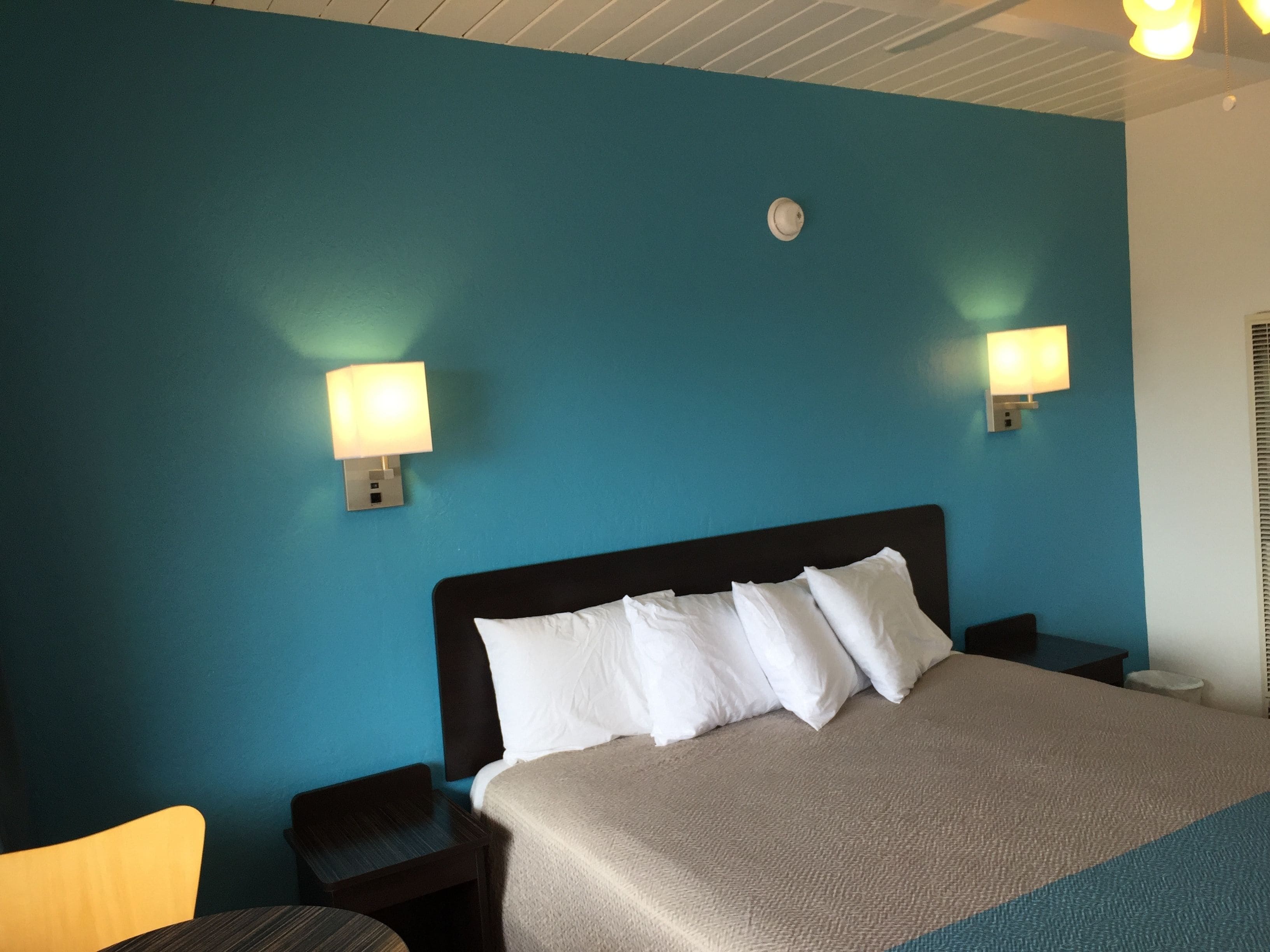 Ein Hotelzimmer mit einem großen Bett, zwei Nachttischen, einem Sessel und Wandleuchten.
