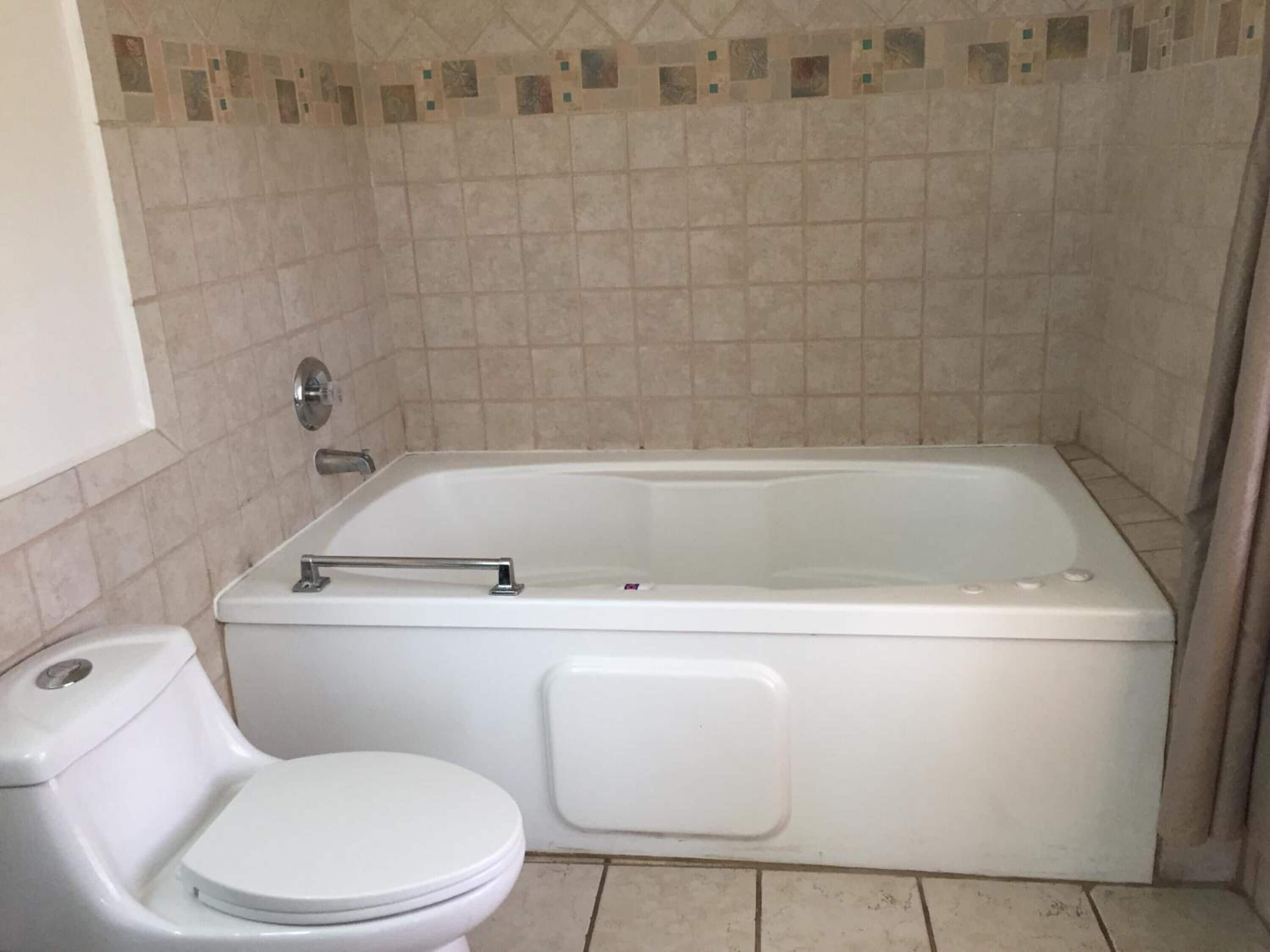Ein Badezimmer mit Badewanne, Toilette und Duschbereich.