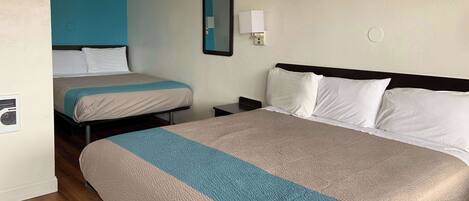 A hotel room with two beds, a nightstand, a wall-mounted mirror, and a ceiling fan.
