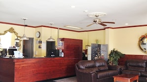 Zona de recepción con mostrador de madera, un reloj, ventilador de techo y asientos de cuero.