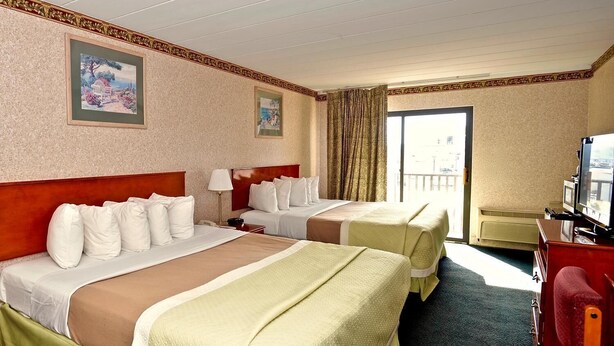 Habitación de hotel con dos camas, televisión, escritorio y balcón.