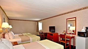 Habitación de hotel con dos camas, un escritorio con computadora, televisor, microondas y cafetera.