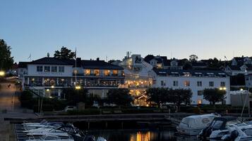 Una marina con barcos amarrados, un edificio frente al agua con un letrero que dice 'Grand Hotel' y un puente al fondo.