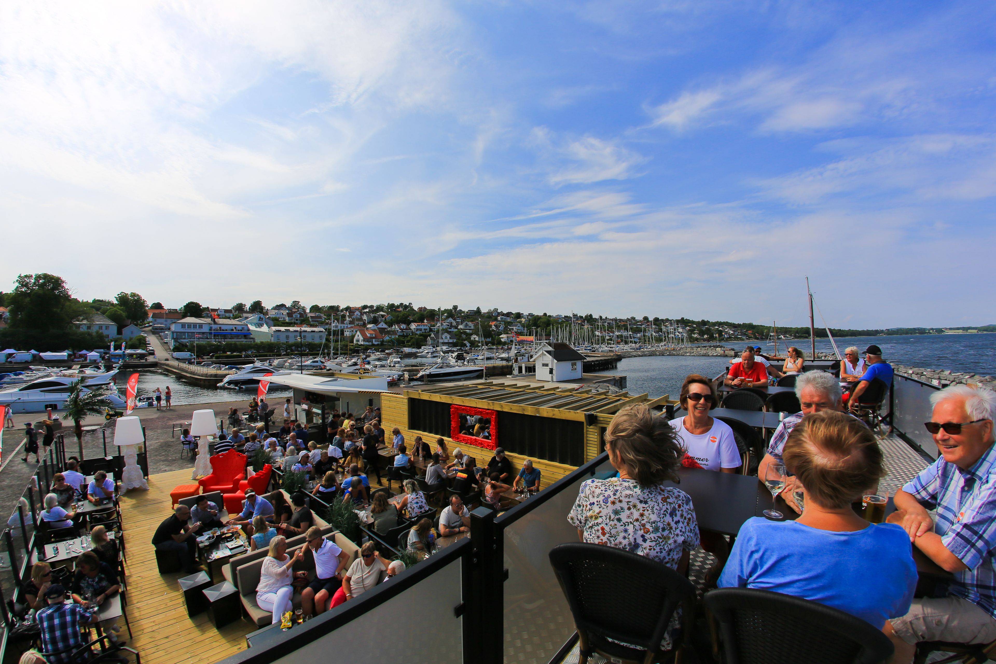 Terraza con mobiliario exterior y vista al puerto deportivo.