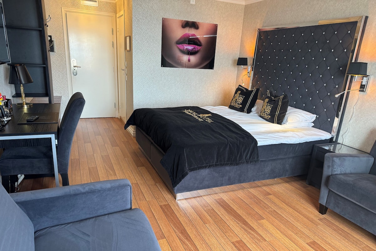 A modern hotel room with a bed, a desk, and a chair.