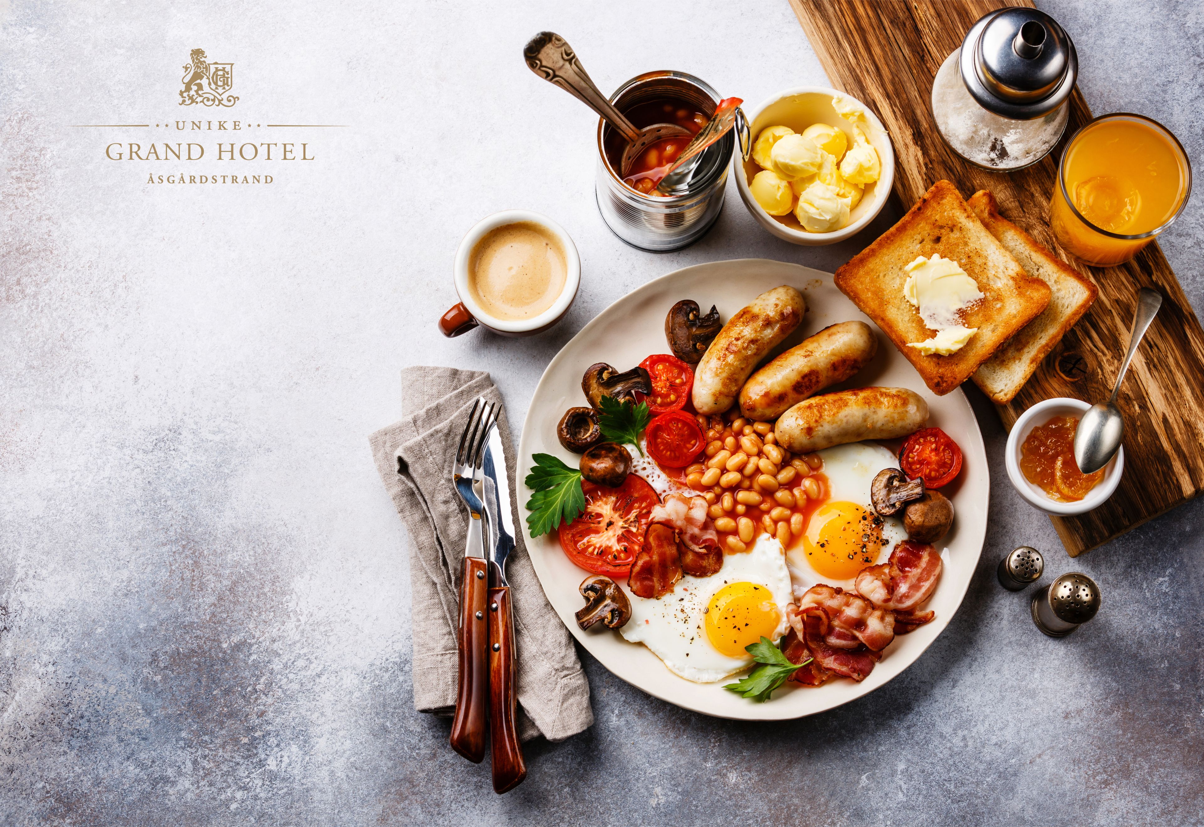 A breakfast plate with eggs, sausages, beans, tomatoes, mushrooms, and toast.