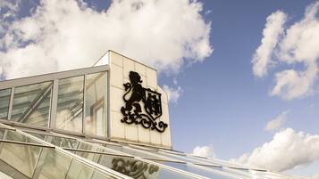 A modern building with a glass facade and a prominent lion statue on the facade.