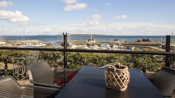 A balcony with a view of a marina, including boats and a distant shoreline. - Grand Hotel Åsgårdstrand - Unike Hoteller (Horten)