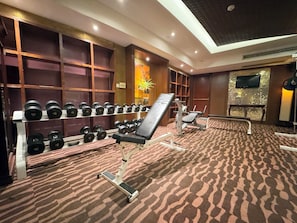 A gym with weight racks, exercise equipment, and a patterned carpet. - voco Changzhou Fudu by IHG (Changzhou)
